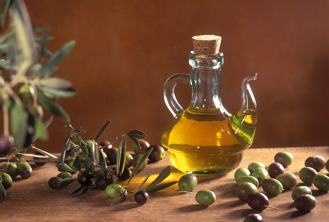Olive oil in a small glass carafe with olives
