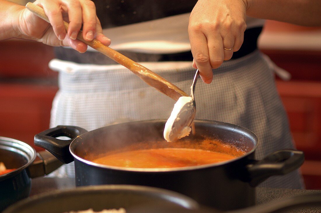 Adding crème fraiche to Camarao na Moranga (pumpkin soup)