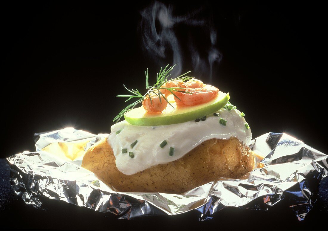 Baked potato on aluminium foil with quark and shrimps