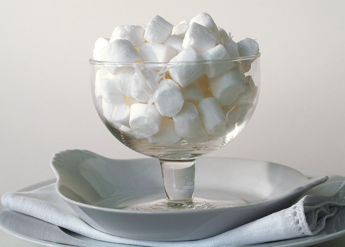 Glass bowl with coconut sweets against white background
