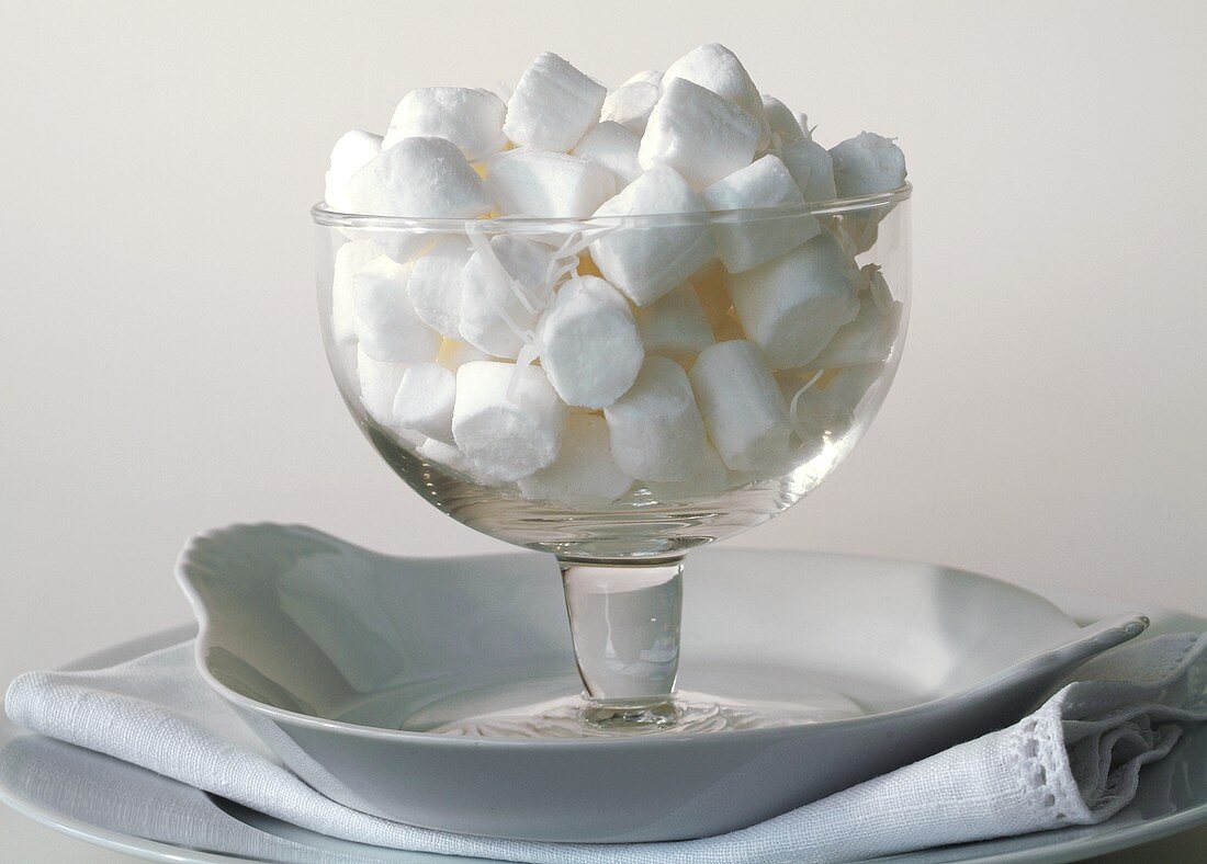 Glasschale mit Kokosnussbonbons vor weißem Hintergrund