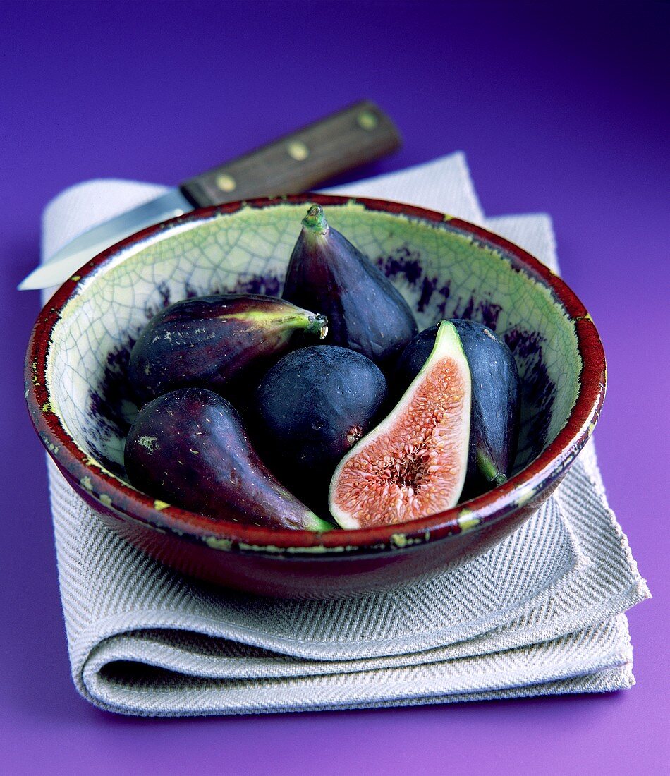 Fresh figs in a china bowl on a cloth, knife