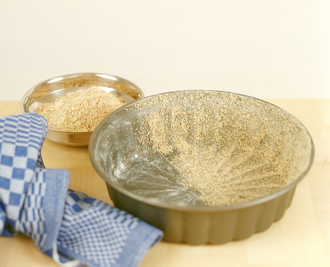 Greasing cake tin and sprinkling with crumbs