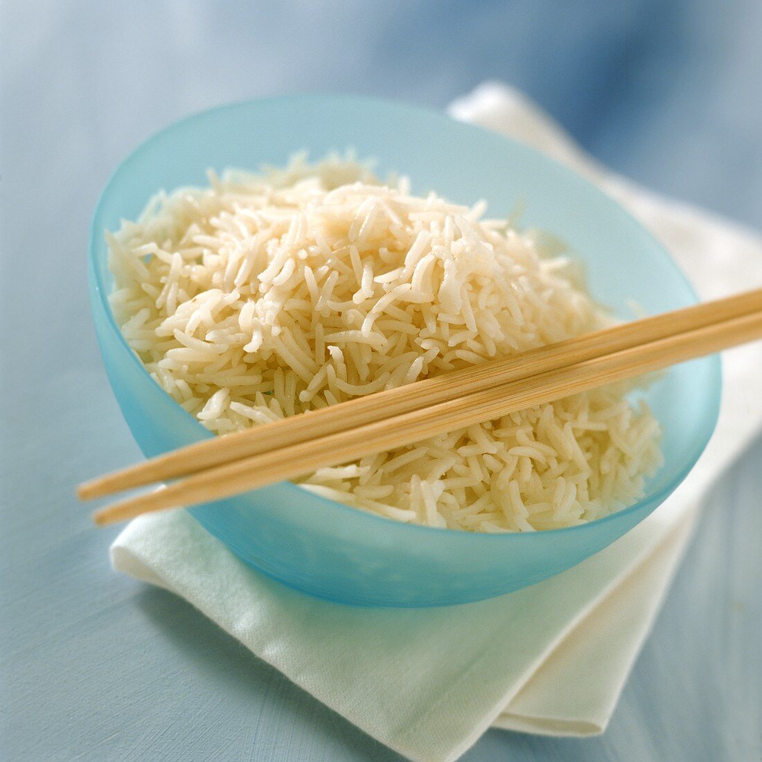 Gekochter Reis in blauer Schale mit Stäbchen