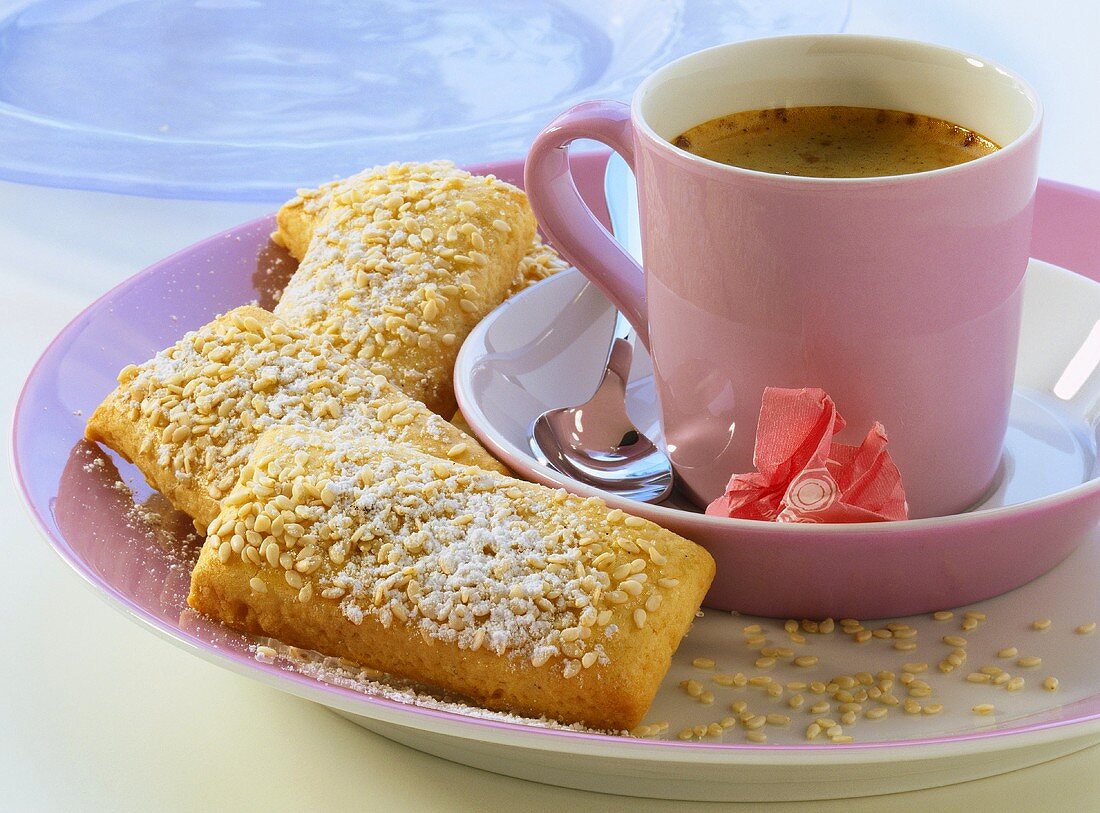 Sesame and ginger sticks with icing sugar; coffee cup