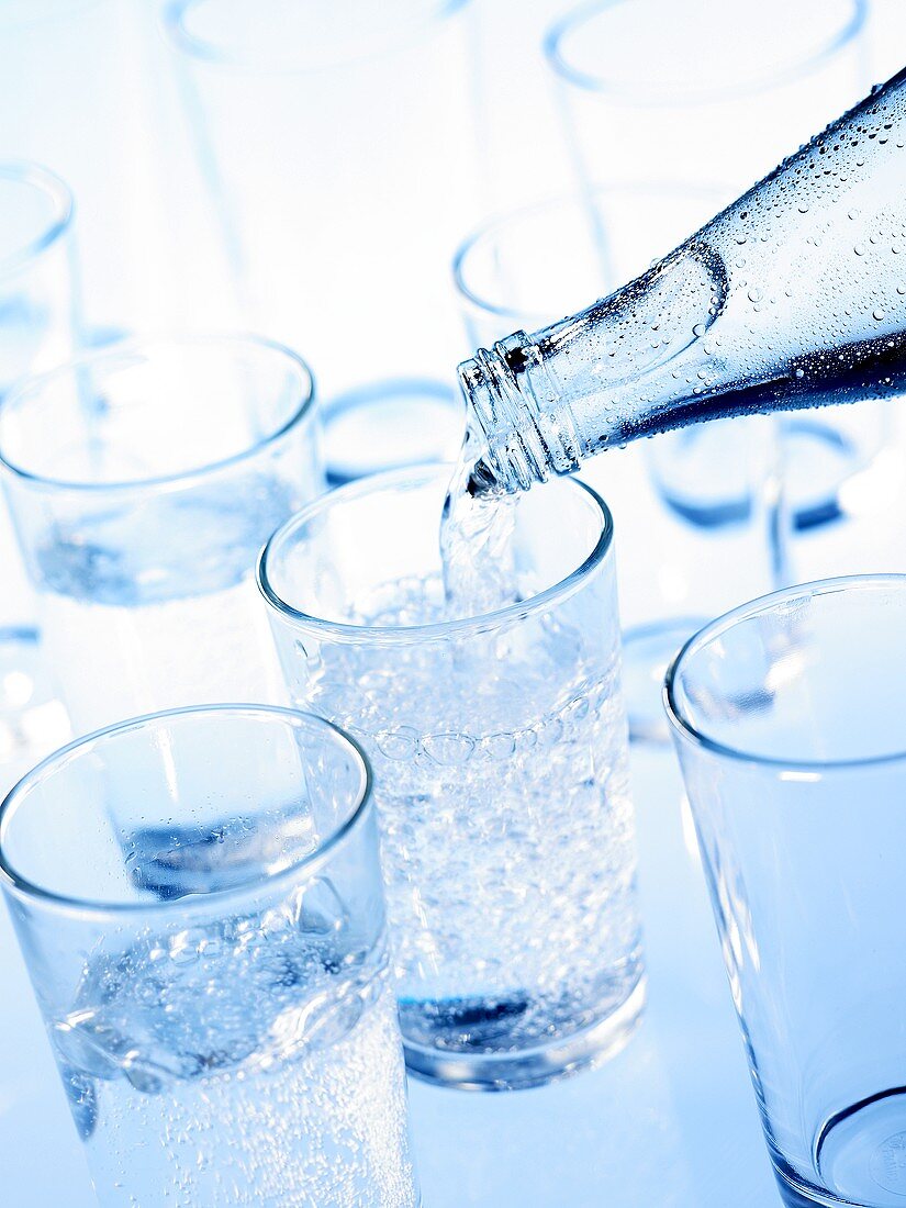 Mineralwasser in Gläser gießen