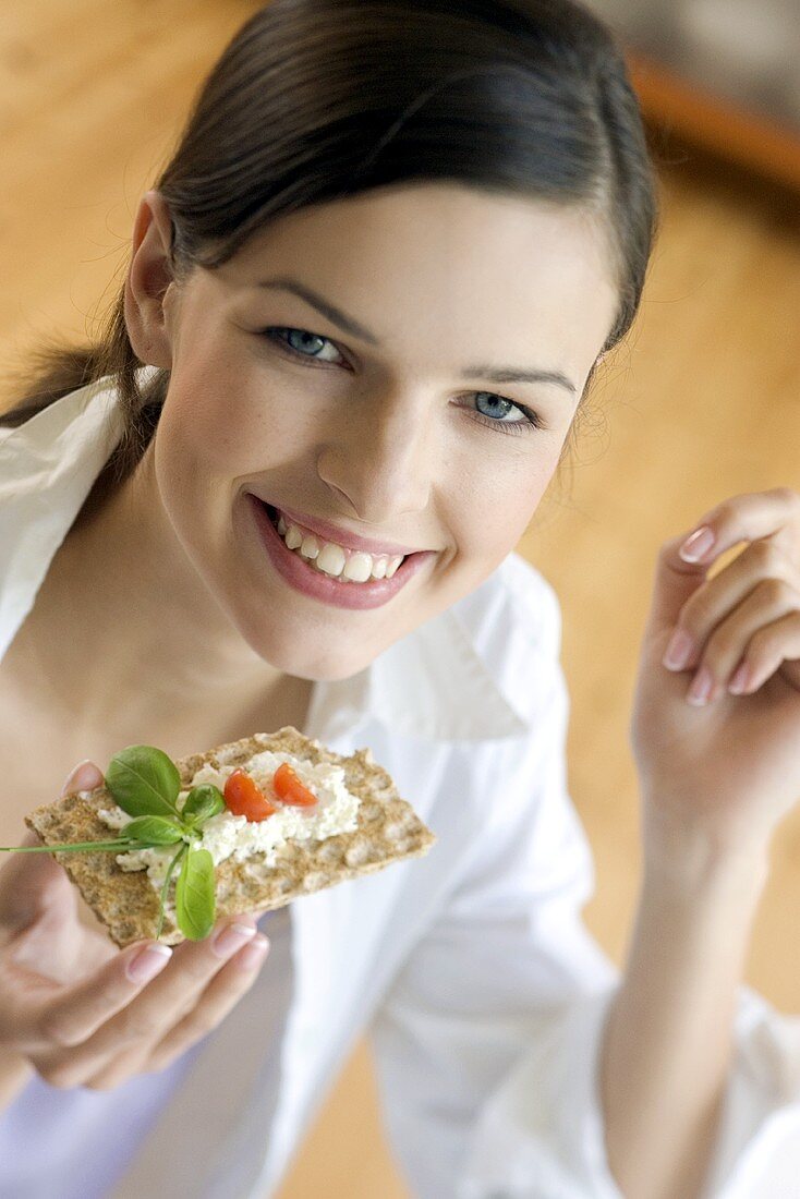 Junge Frau isst Knäckebrot mit Kräuterquark