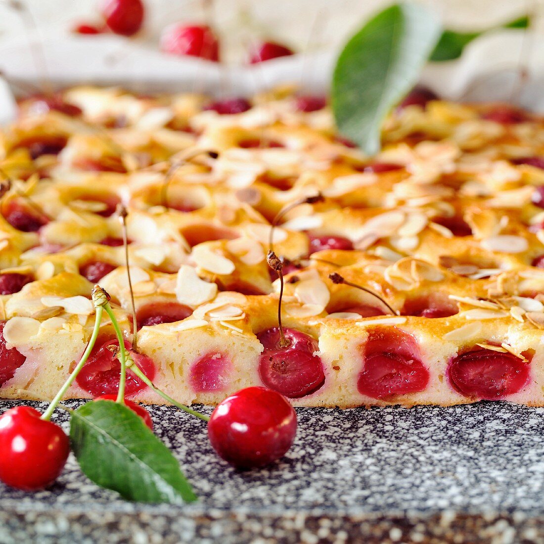 Tray-baked cake with sweet cherries & almonds (a piece cut)