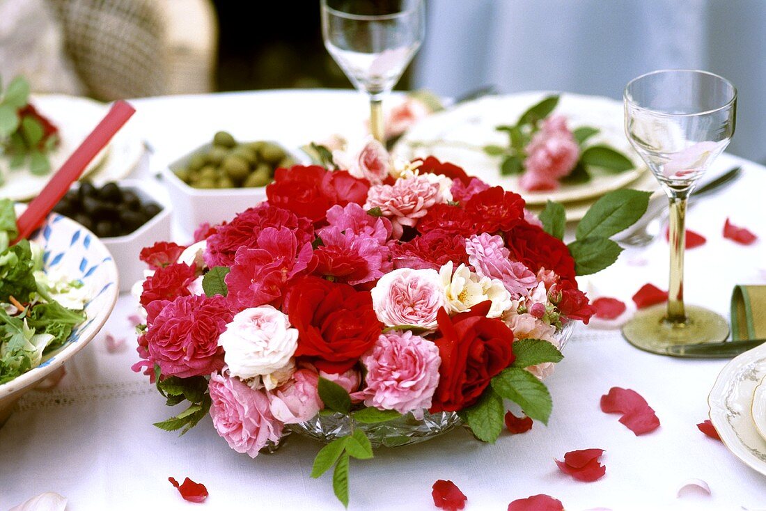 Schale mit Rosenblüten auf festlich gedecktem Tisch