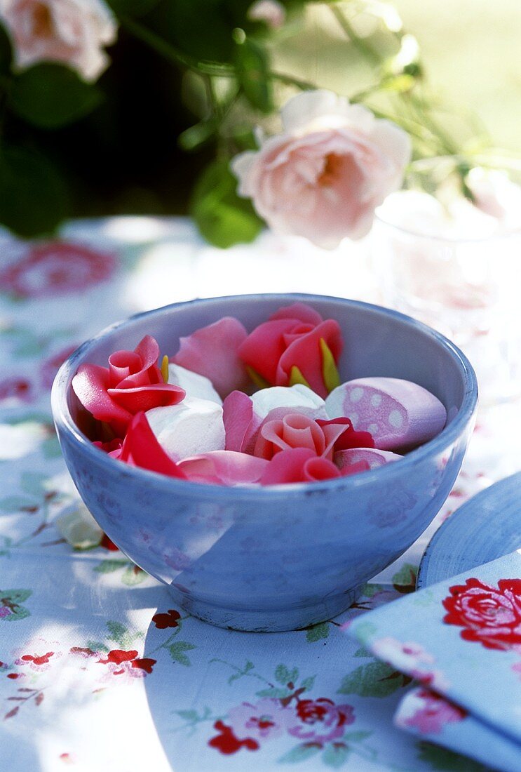 Bowl of marzipan roses and marshmallow on summery table