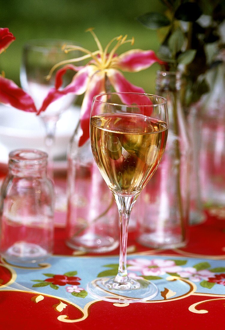 A glass of white wine on colourful laid table in open air