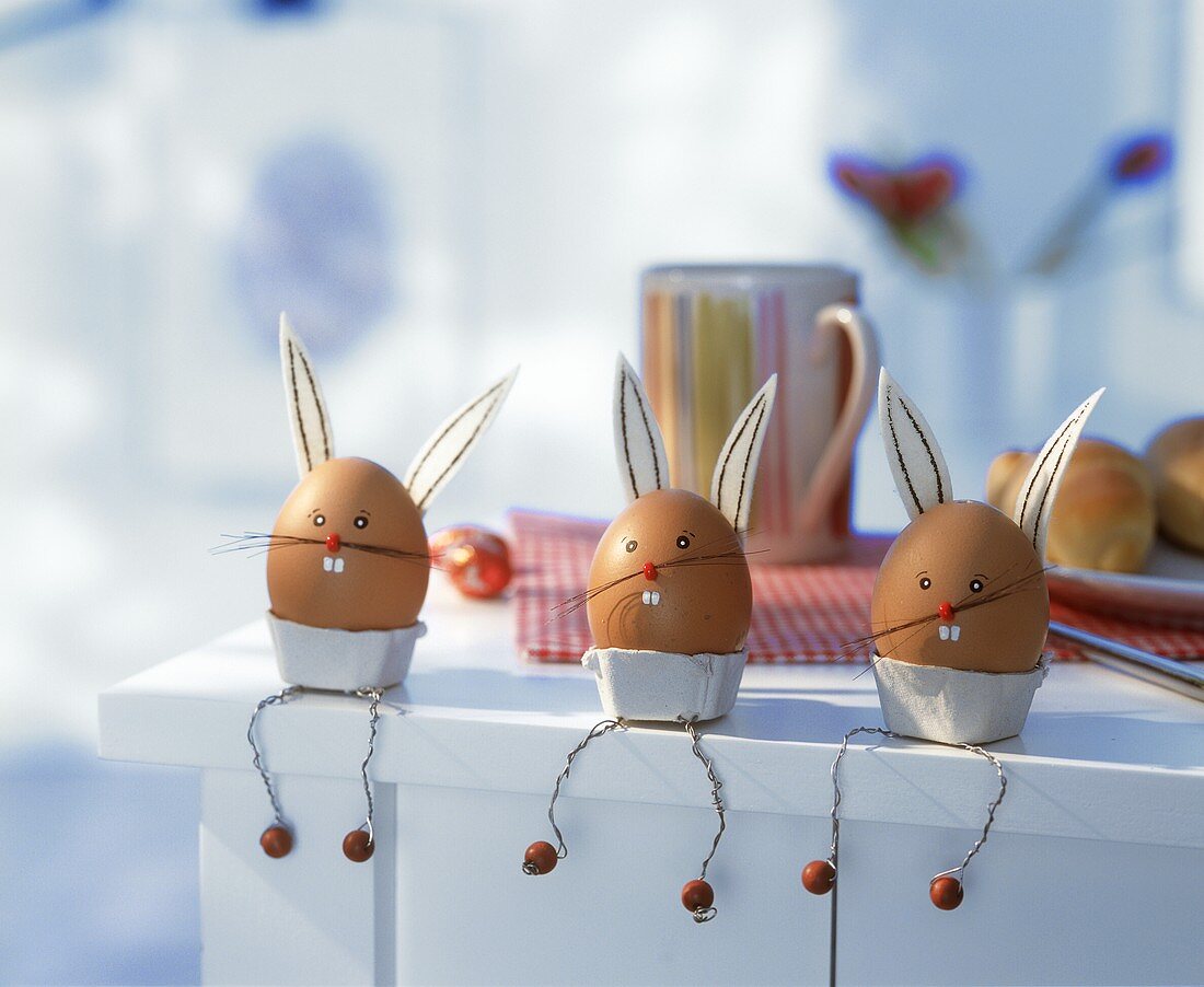 Three eggs decorated as Easter Bunnies sitting on edge of table