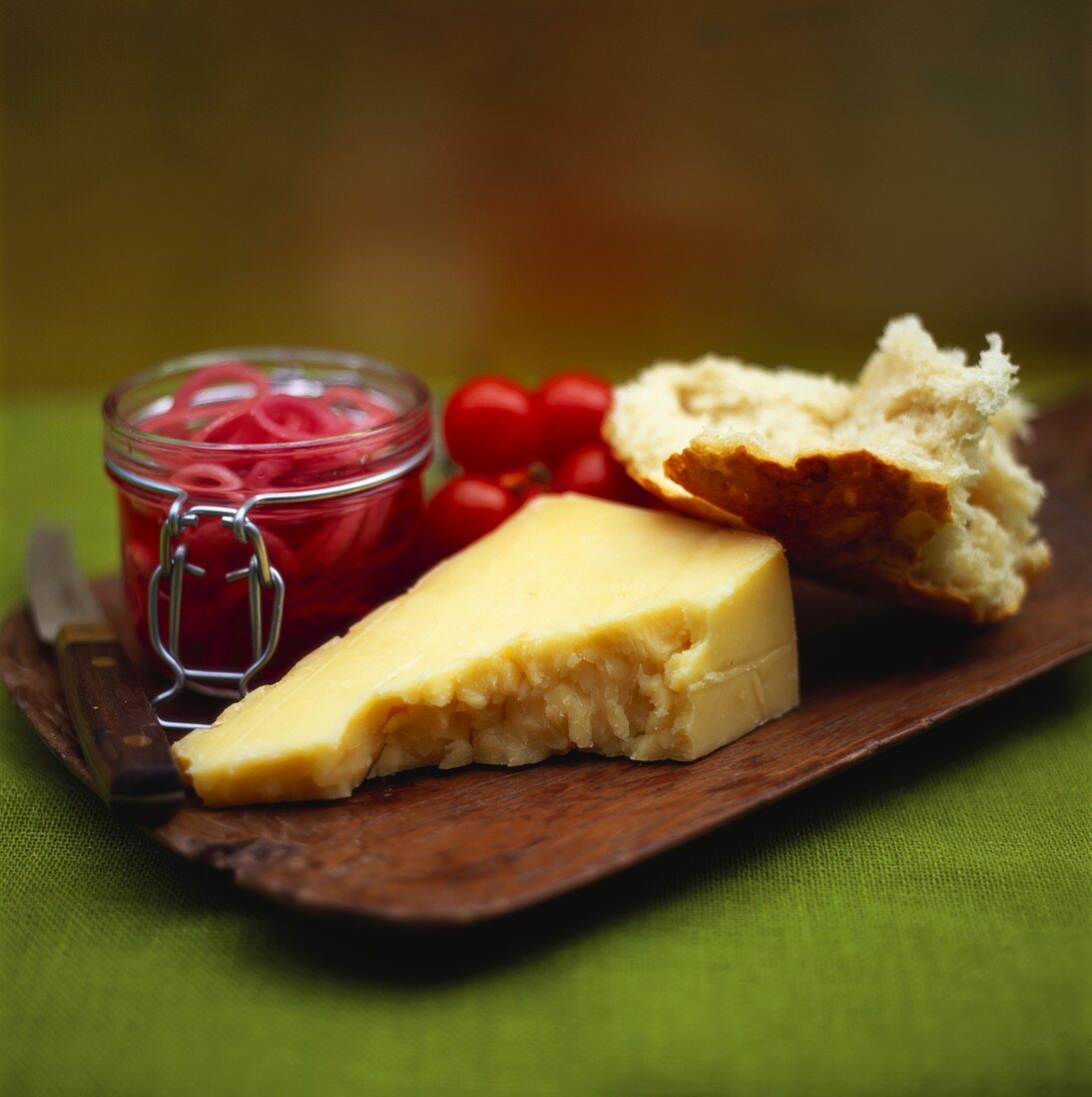 Board with cheese, bread, marinated onions and tomatoes