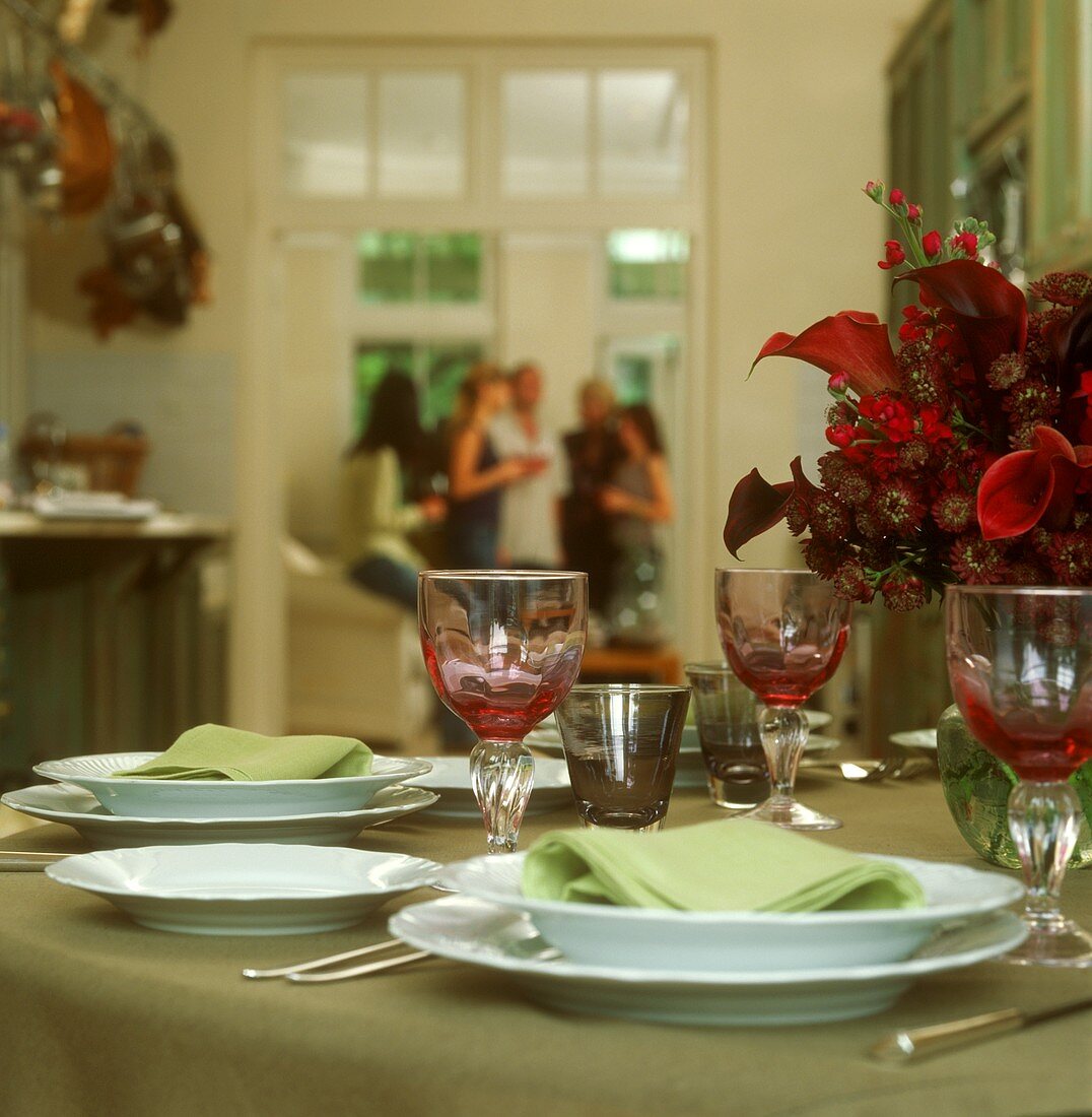 Gedeckter Tisch in Grün und Rot, im Hintergrund Menschen