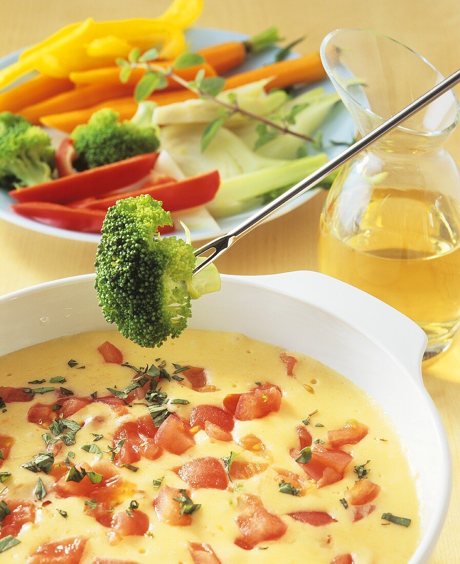 Dipping vegetables into cheese and tomato fondue