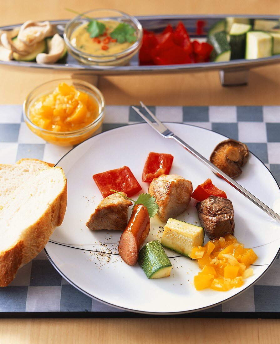 Klassisches Fondue mit Fleisch- und Gemüsehappen sowie Saucen