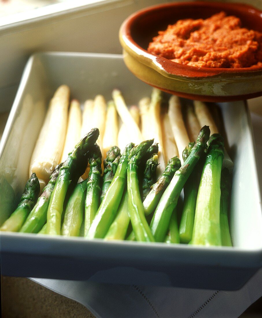 Green and white asparagus in a bowl and chili sauce