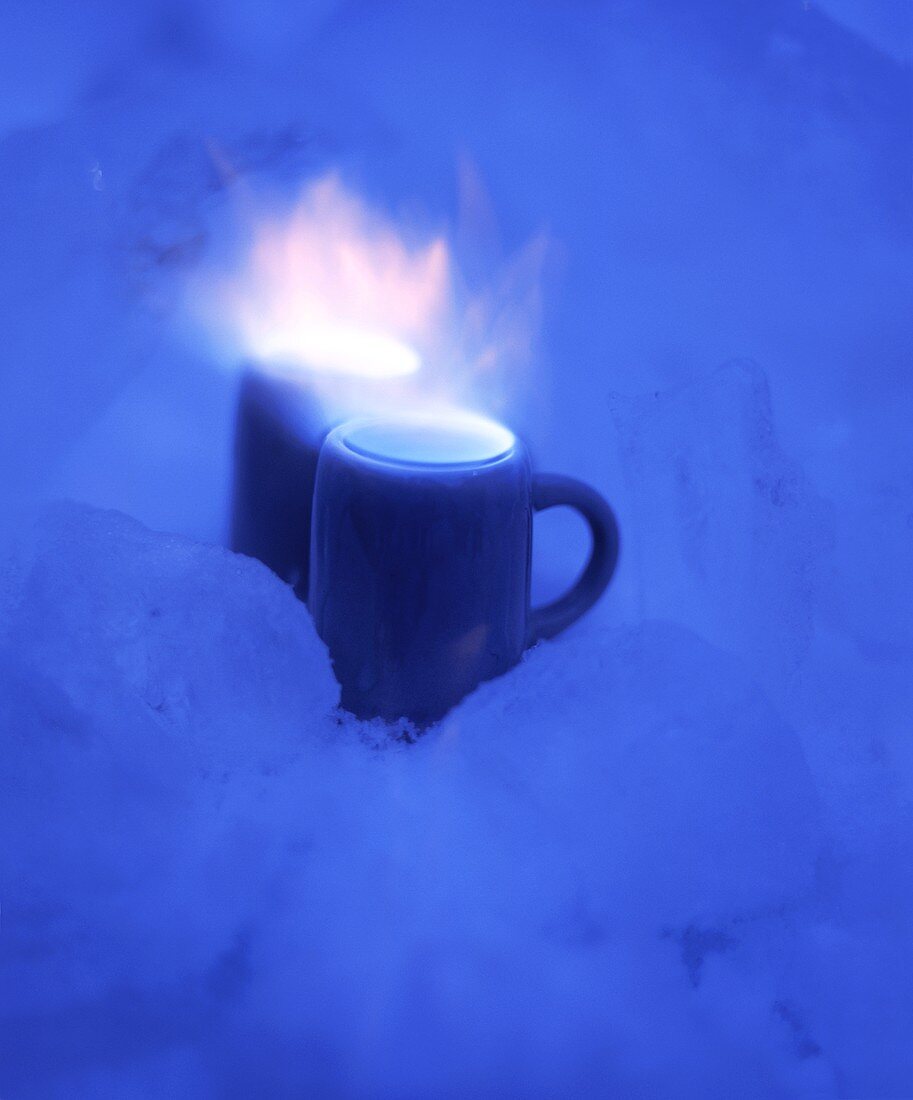 Two small mugs of burning schnapps in snow