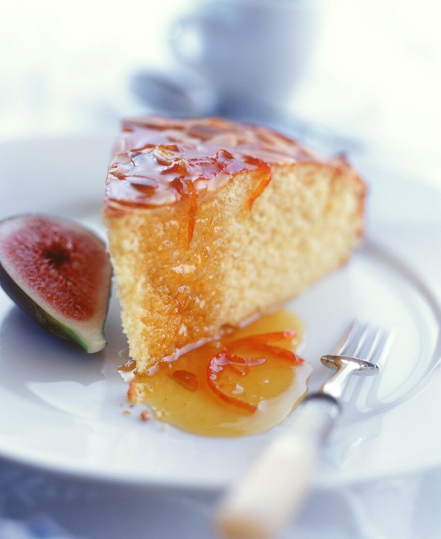 Piece of rich sponge cake with orange sauce; half a fig