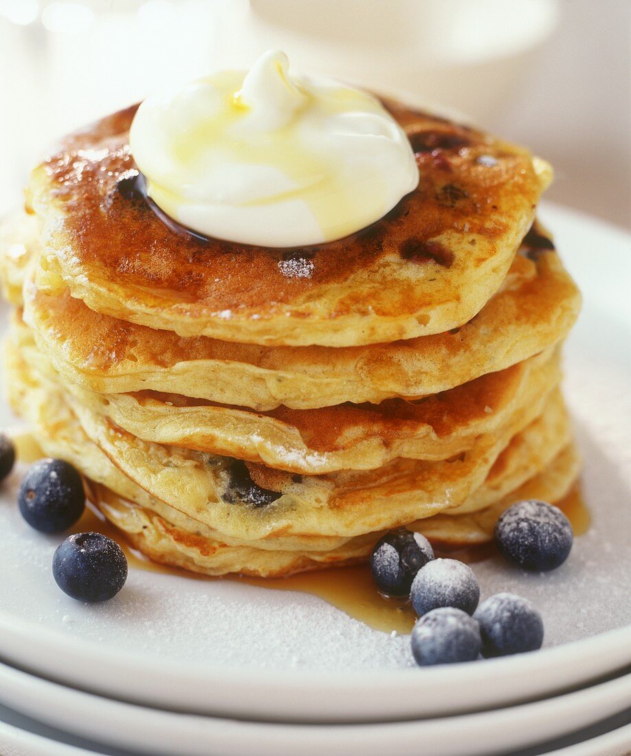 Pile of pancakes with maple syrup and blueberries