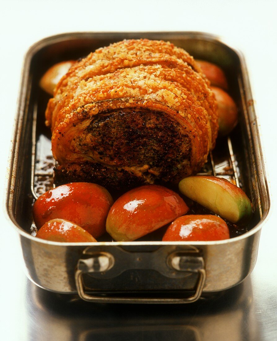 Roast pork roll with crackling on apple quarters
