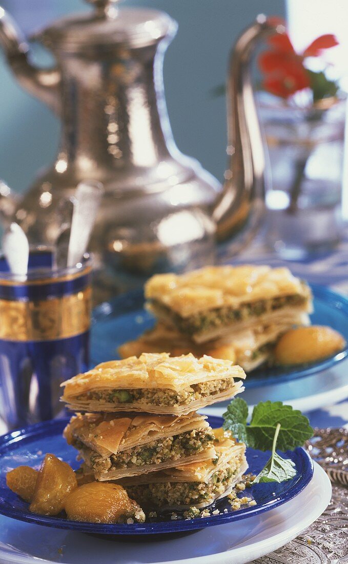 Pieces of baklava on a plate with apricots and mint leaves