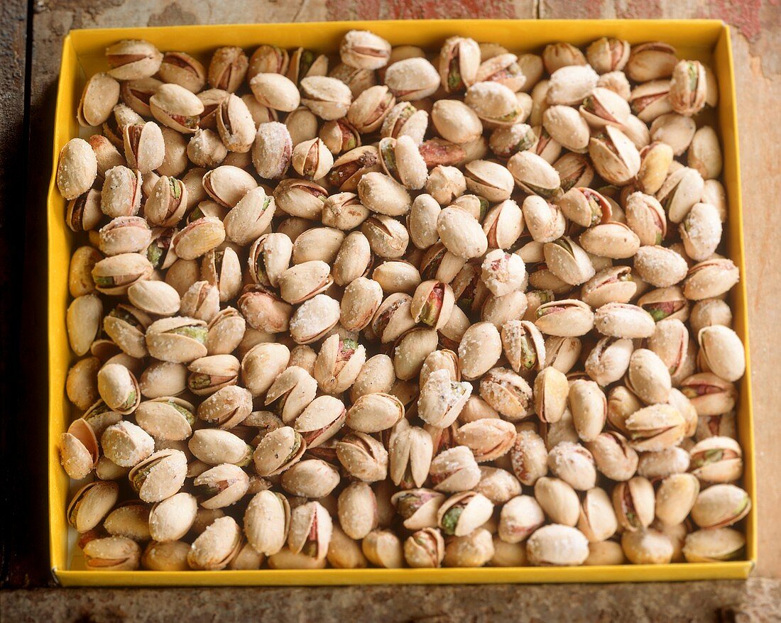 Roasted and salted pistachios in a yellow cardboard box