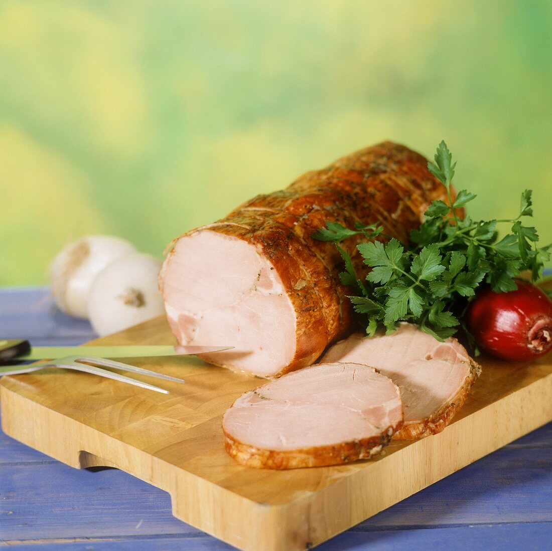 Cold roast pork roll on wooden board, carved