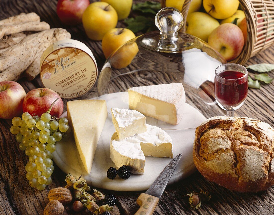 Käseplatte mit französischem Käse, Laib Brot und Glas Rotwein
