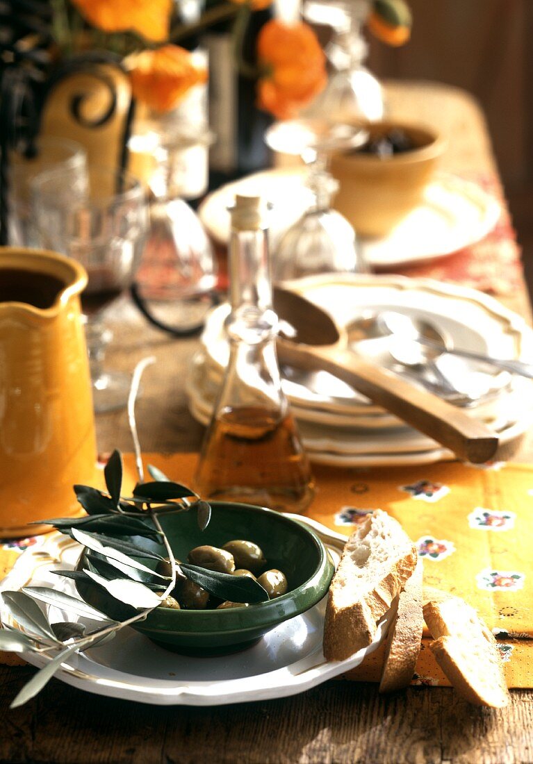 Table laid in country house style, bowl of olives, bread