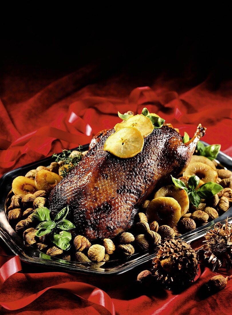 Christmas goose on bed of chestnuts with slices of fruit