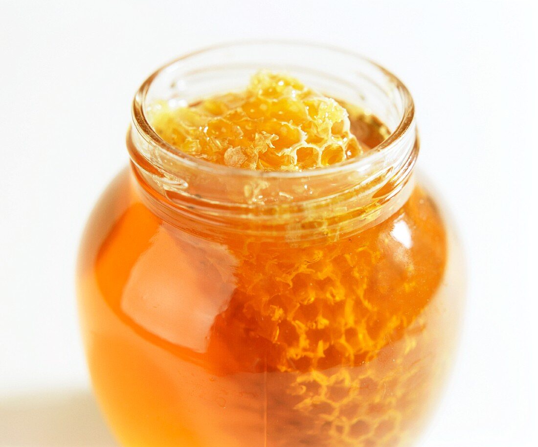Glas mit frischem Bienehonig und Bienenwabe