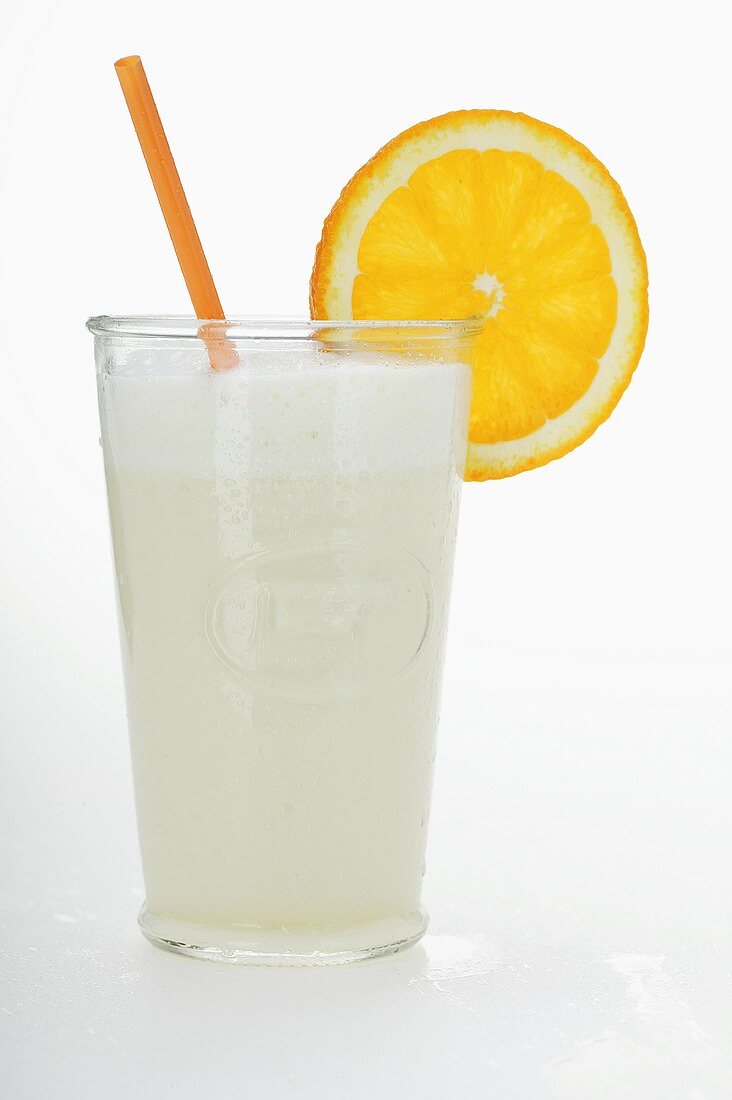 A glass of orange milkshake with straw