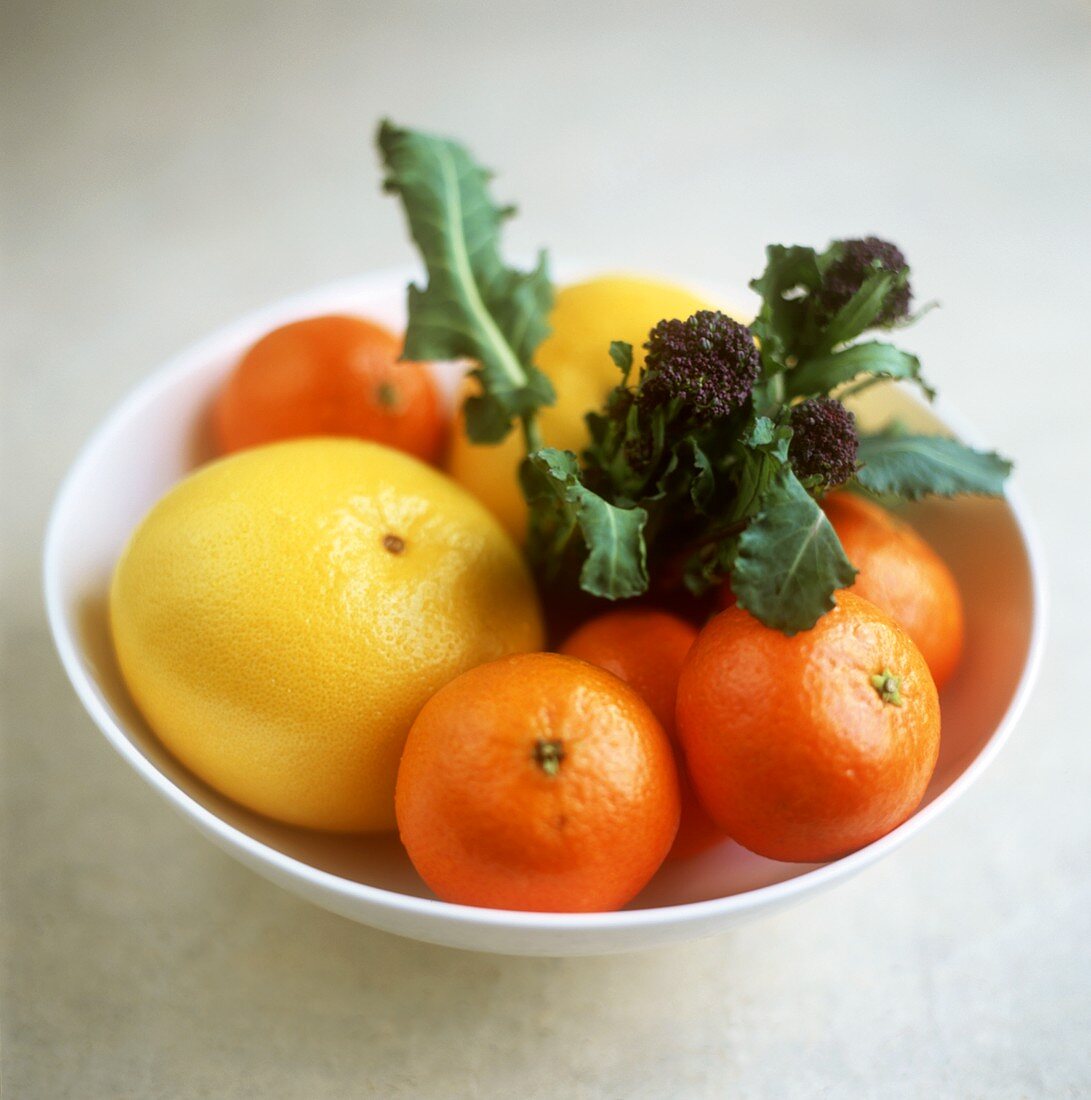 Bowl of citrus fruits and purple broccoli