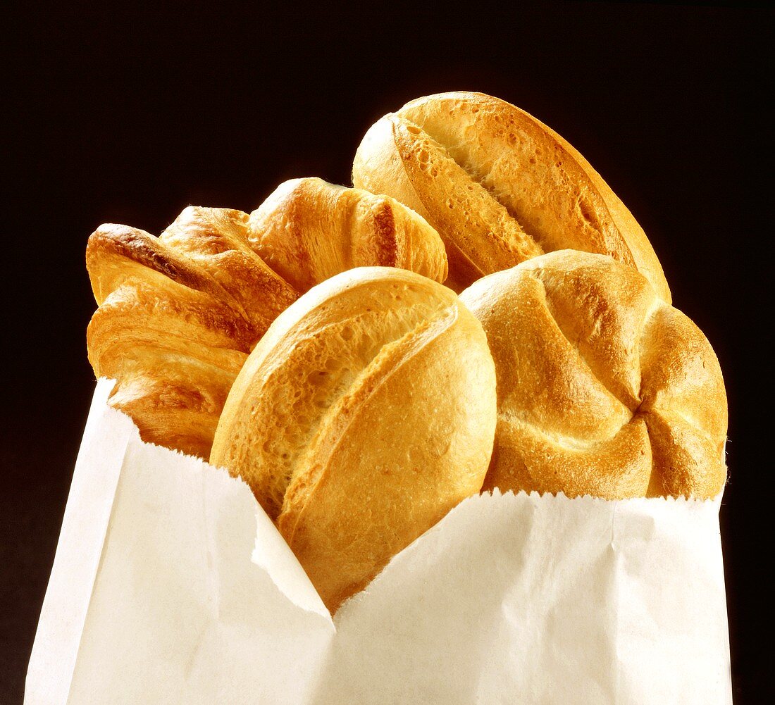 Helle Brötchen und Croissant in Papiertüte