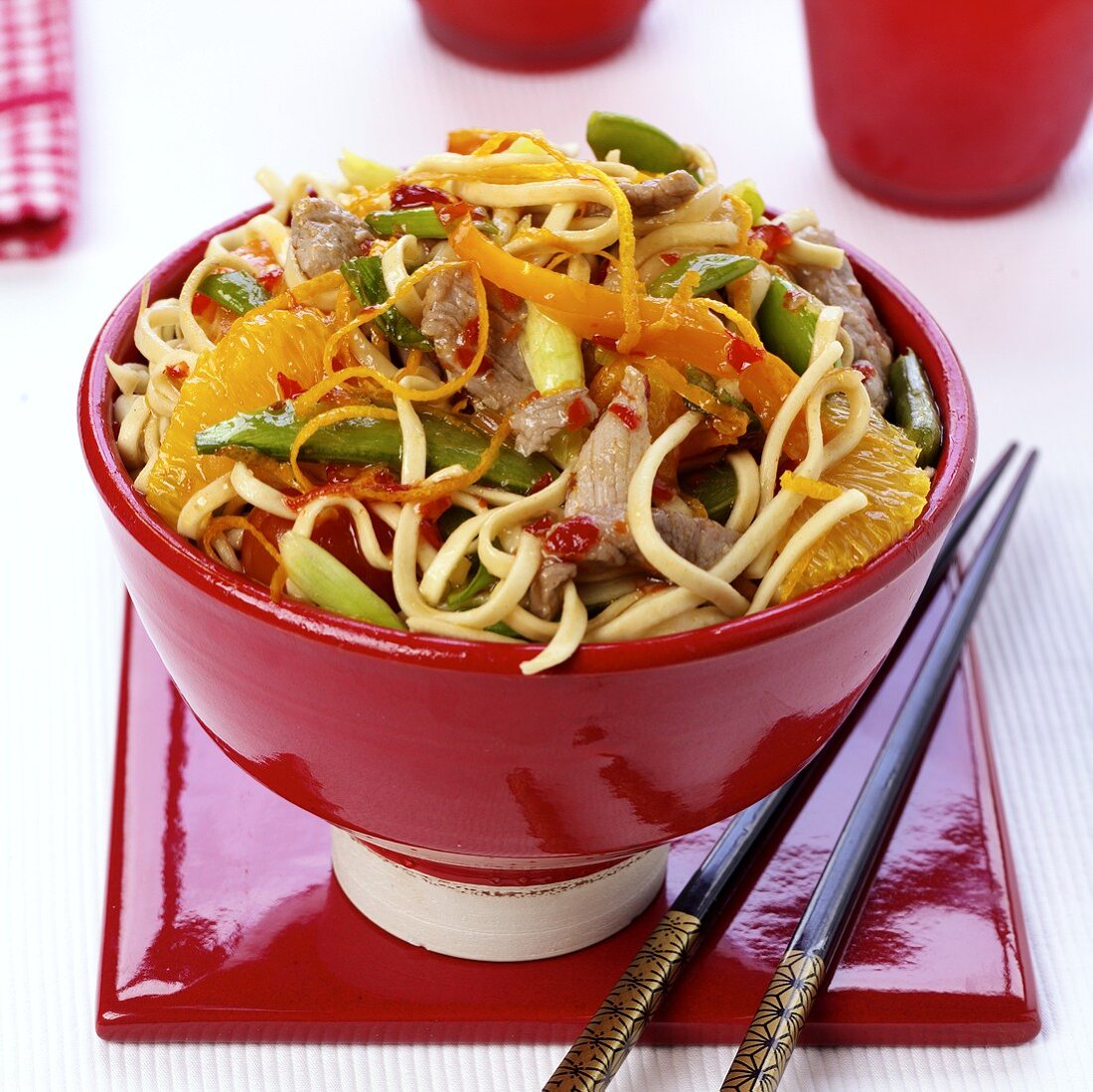 Asian noodles with pork, vegetables and oranges