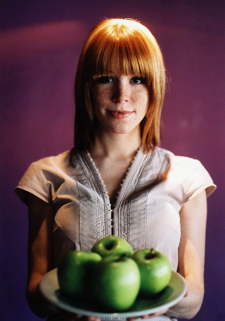 Frau hält Teller mit grünen Äpfeln (Grainy Effect)