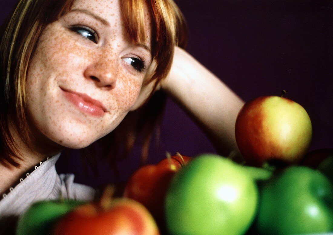 Junge Frau schaut vergnügt auf frische Äpfel