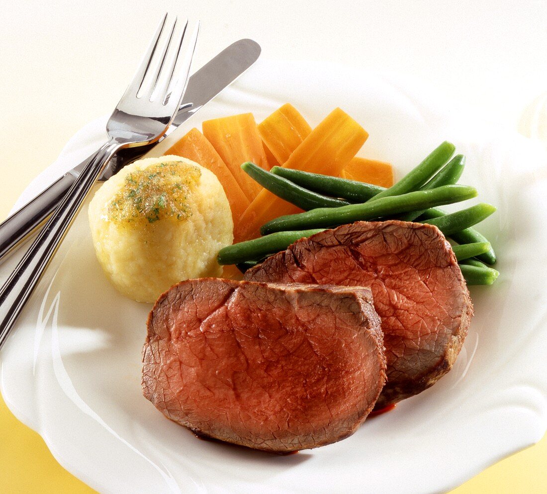 Two slices of roast beef with a dumpling and vegetables