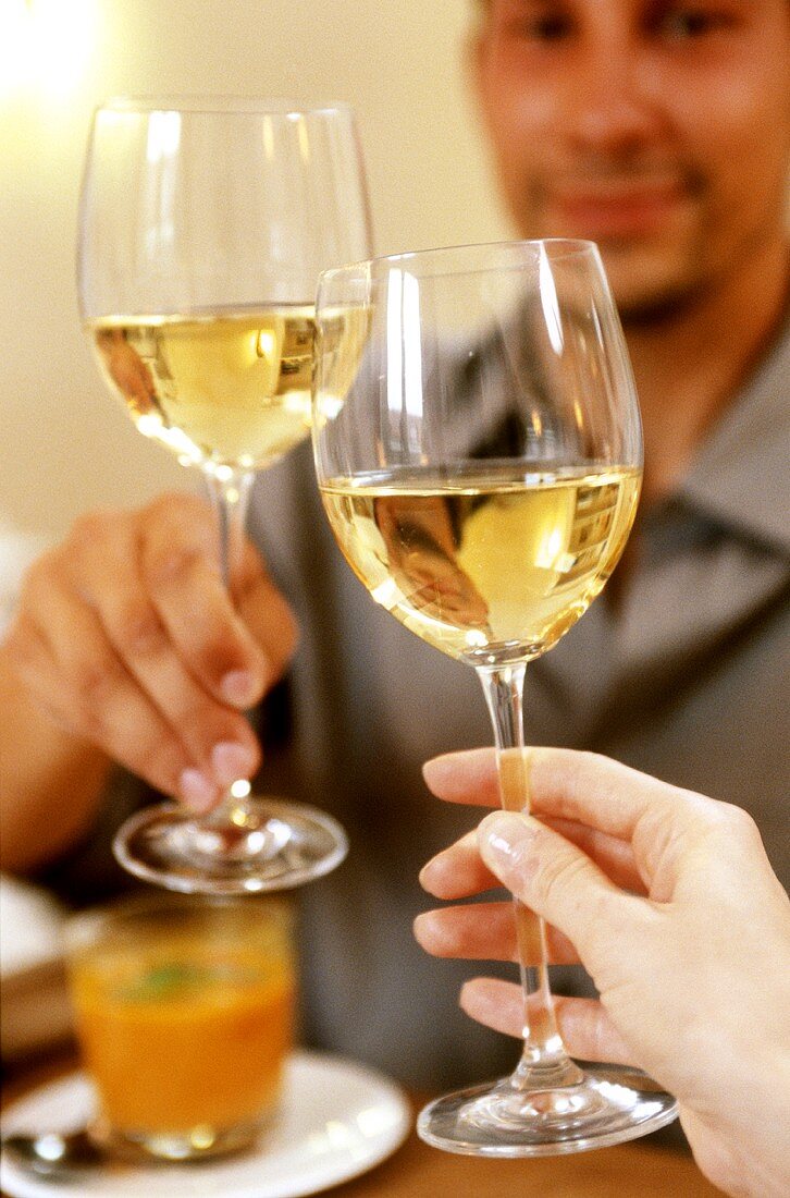 Man chinking white wine glass