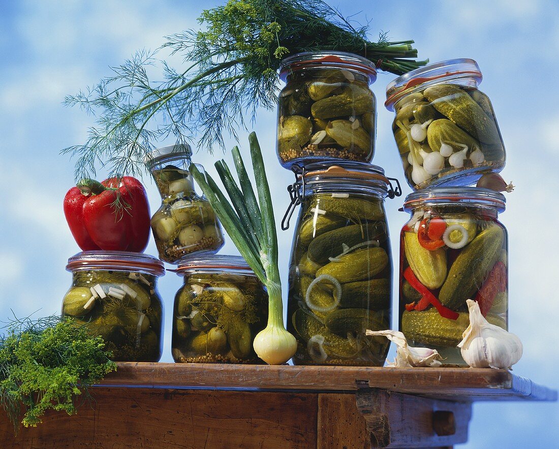 Pickled gherkins in jars on wooden table
