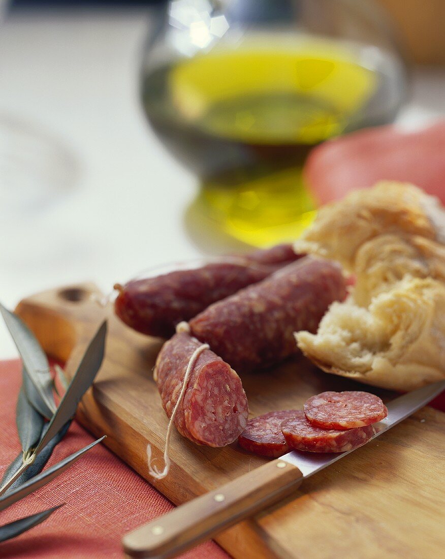 Stillleben mit kleinen italienischen Salami, Messer und Brot