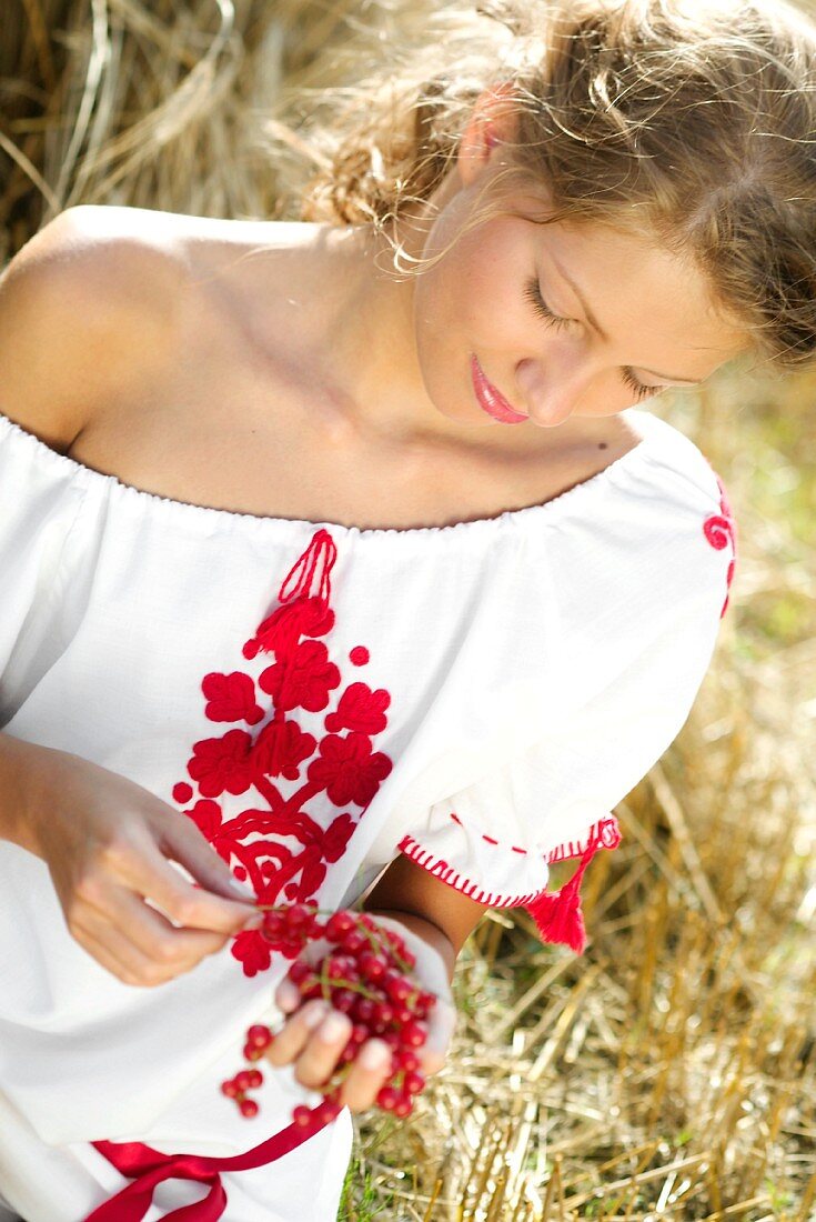 Young woman holding redcurrants in her hands