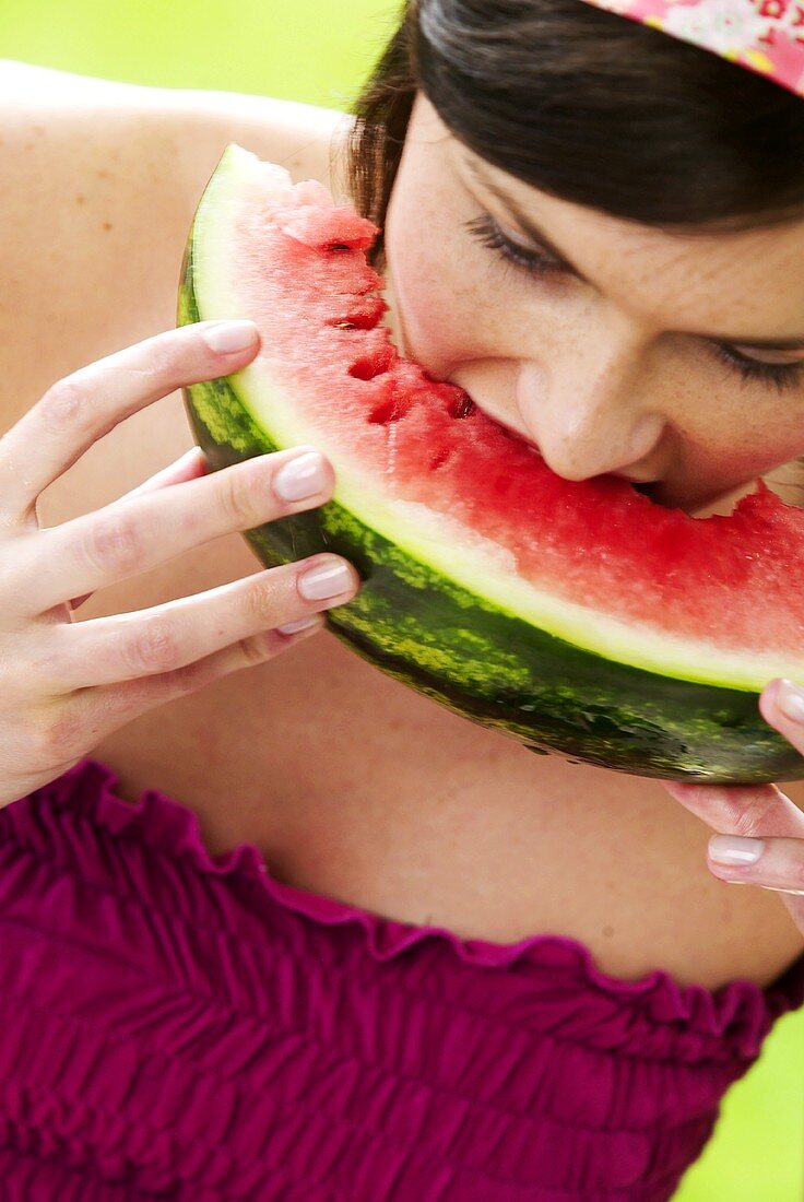Frau hält beisst in ein Stück Melone