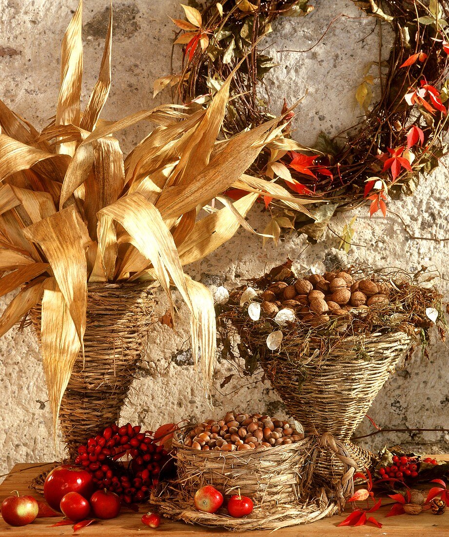 Wicker basket with maize leaves, nuts & autumn decoration