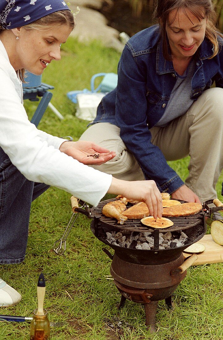 Two young women barbecuing out of doors