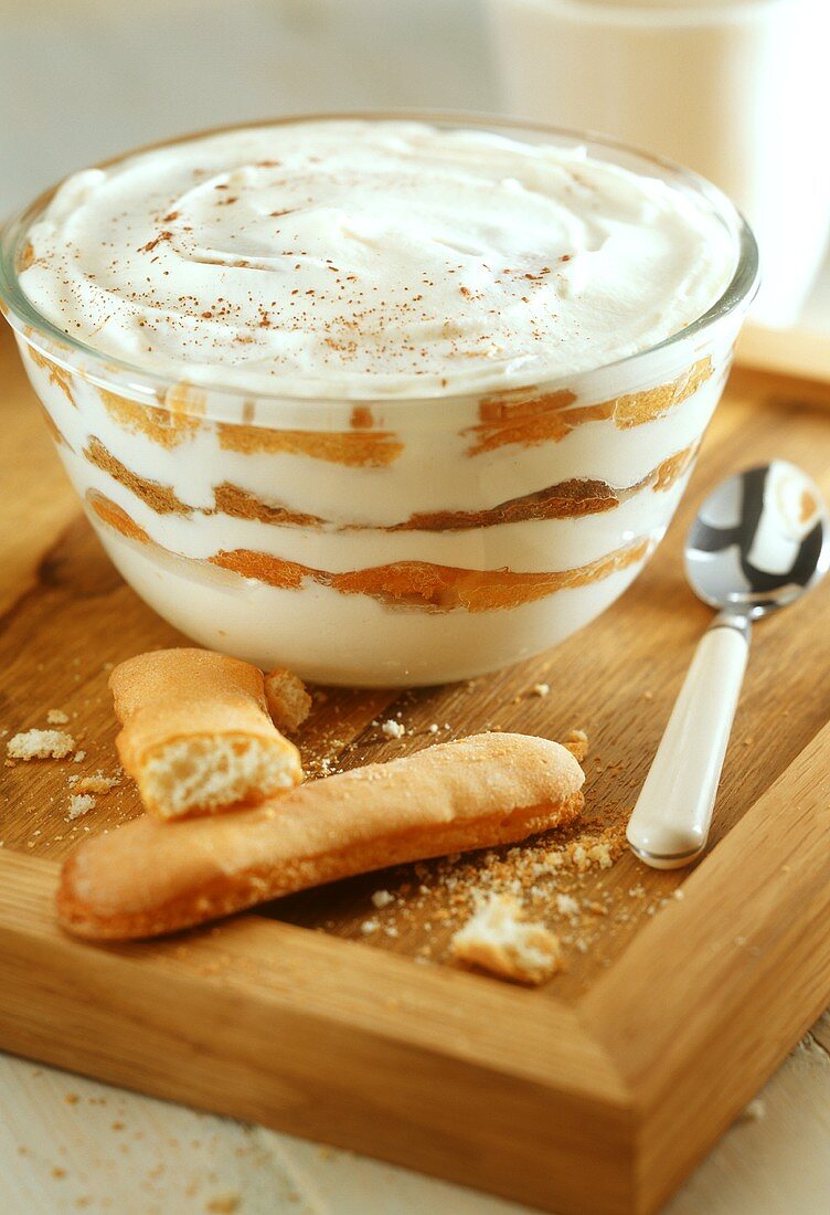 Tiramisu in a glass dish, sponge fingers in front