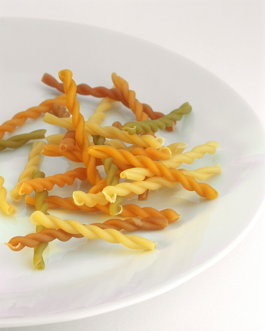 Coloured fusilli on white plate