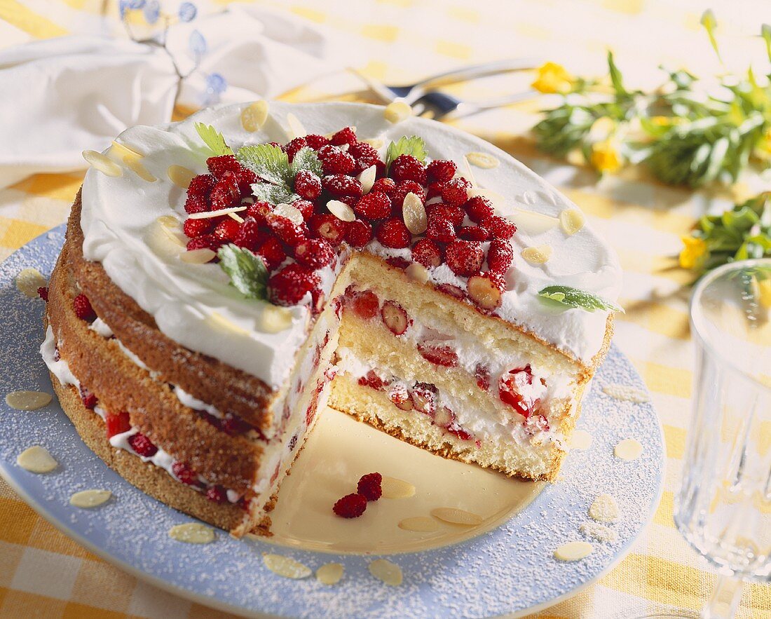 Cream cake with wild strawberries, a piece cut