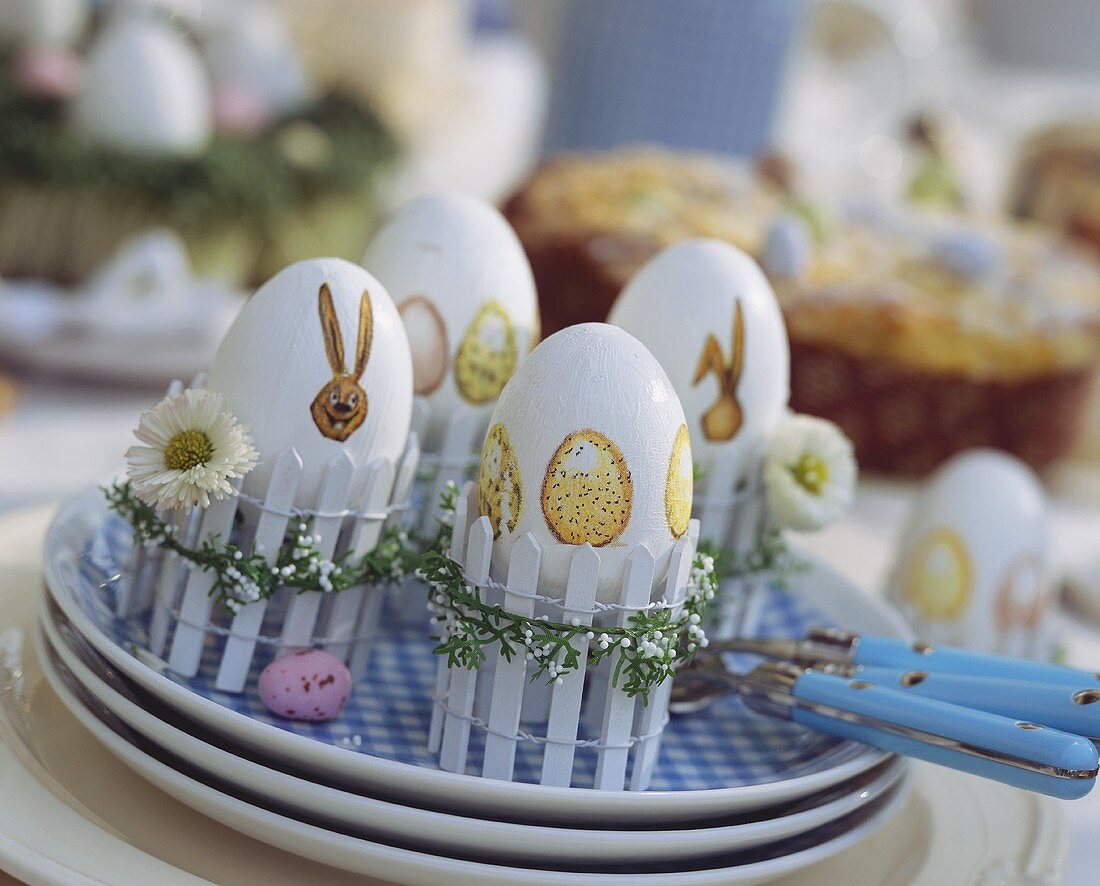 Ostereier in dekorativen Eierbechern (aus Mini-Zäunen)
